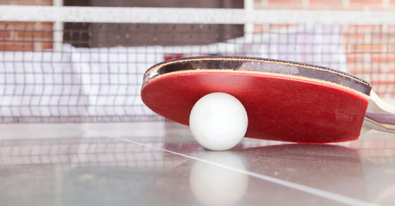 Table tennis racket and white ball on ping pong table