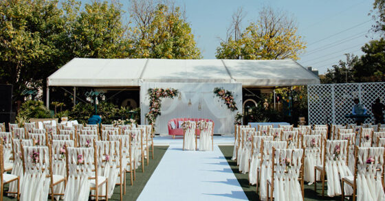 Outdoor wedding setup with floral stage and guest seating.